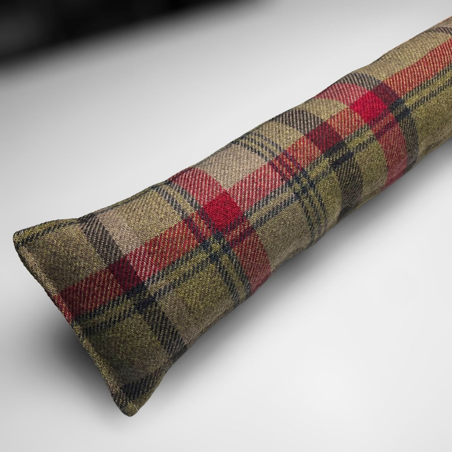 Handmade wool tartan draught excluder in green, red, and brown tones, designed to block drafts under doors.
