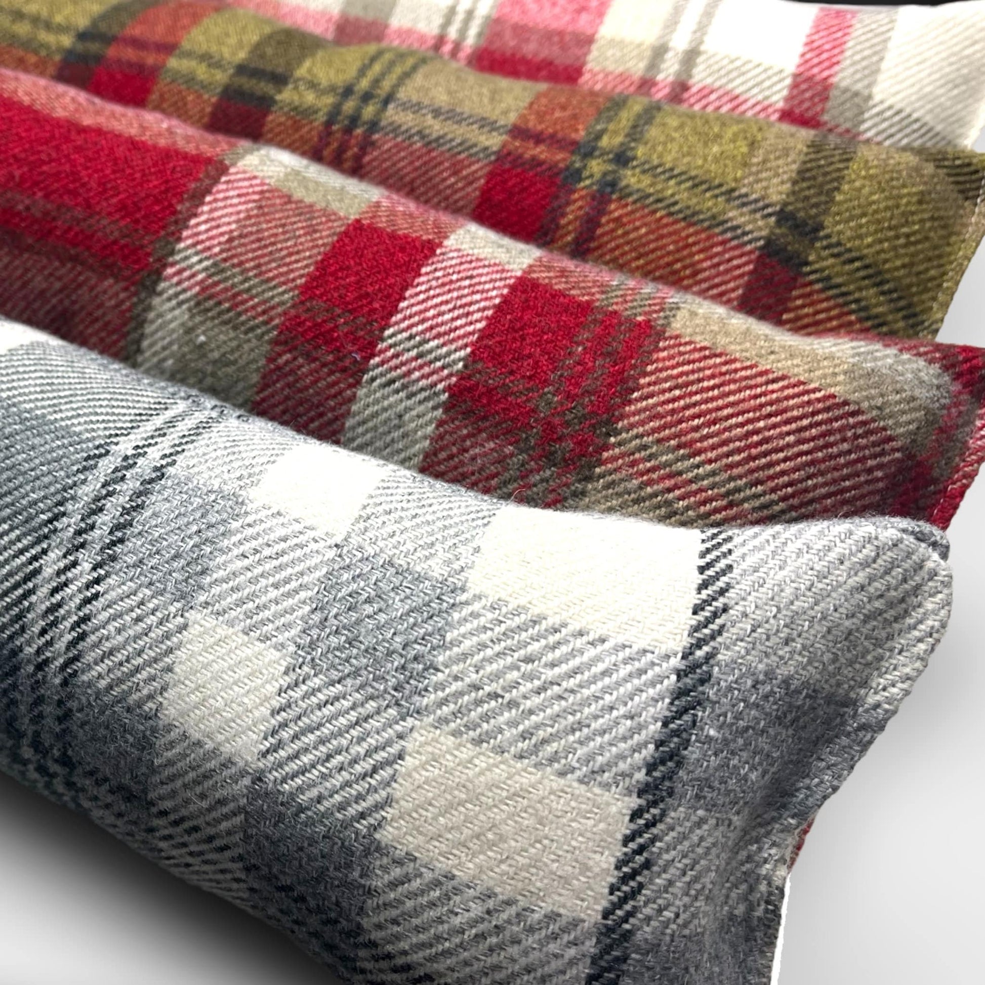 Handmade wool tartan draught excluder in green, red, and brown tones, designed to block drafts under doors.