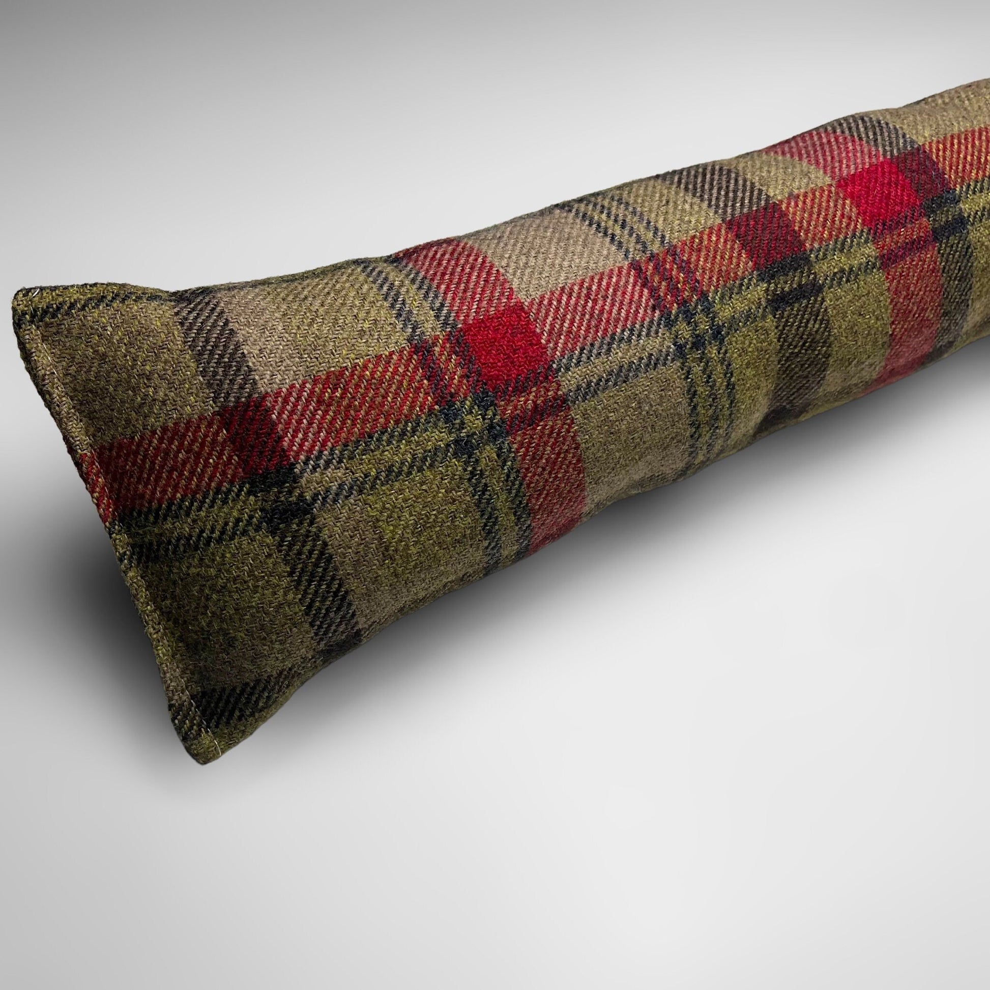 Handmade wool tartan draught excluder in green, red, and brown tones, designed to block drafts under doors.